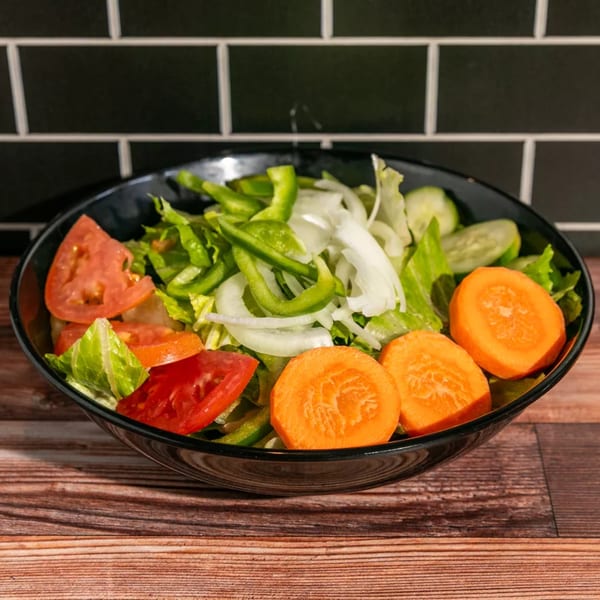 Fresh garden salad with lettuce, tomatoes, carrots, onions, and bell peppers in a black bowl.
