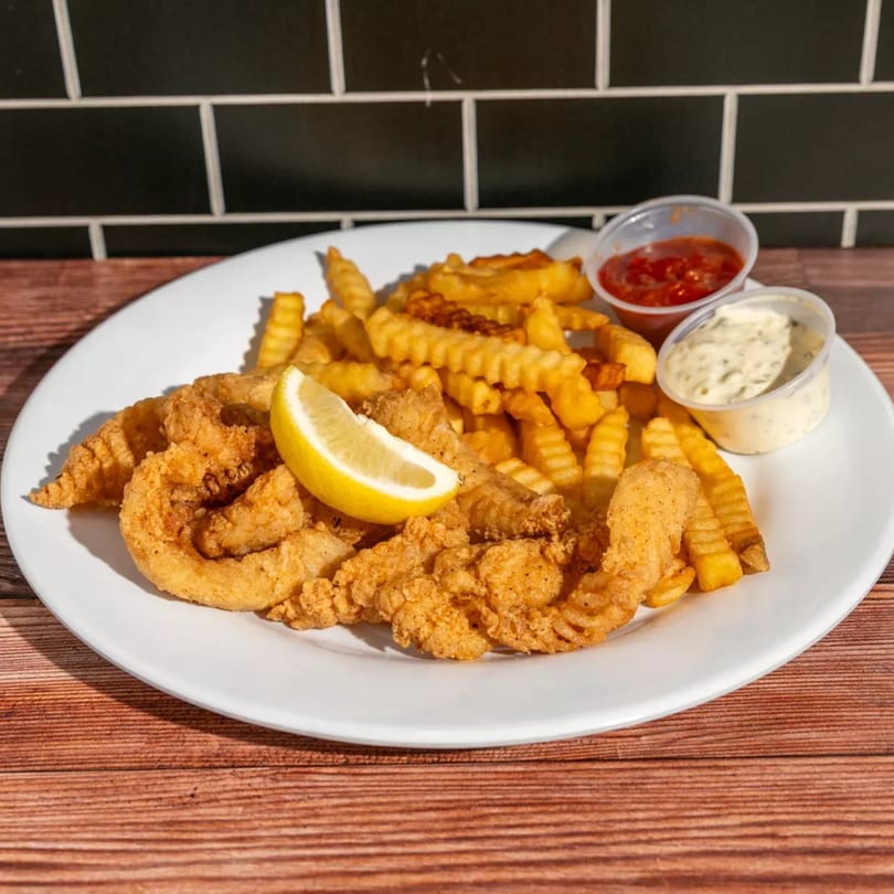 Crispy fried shrimp and crinkle-cut fries with a lemon wedge, ketchup, and tartar sauce.